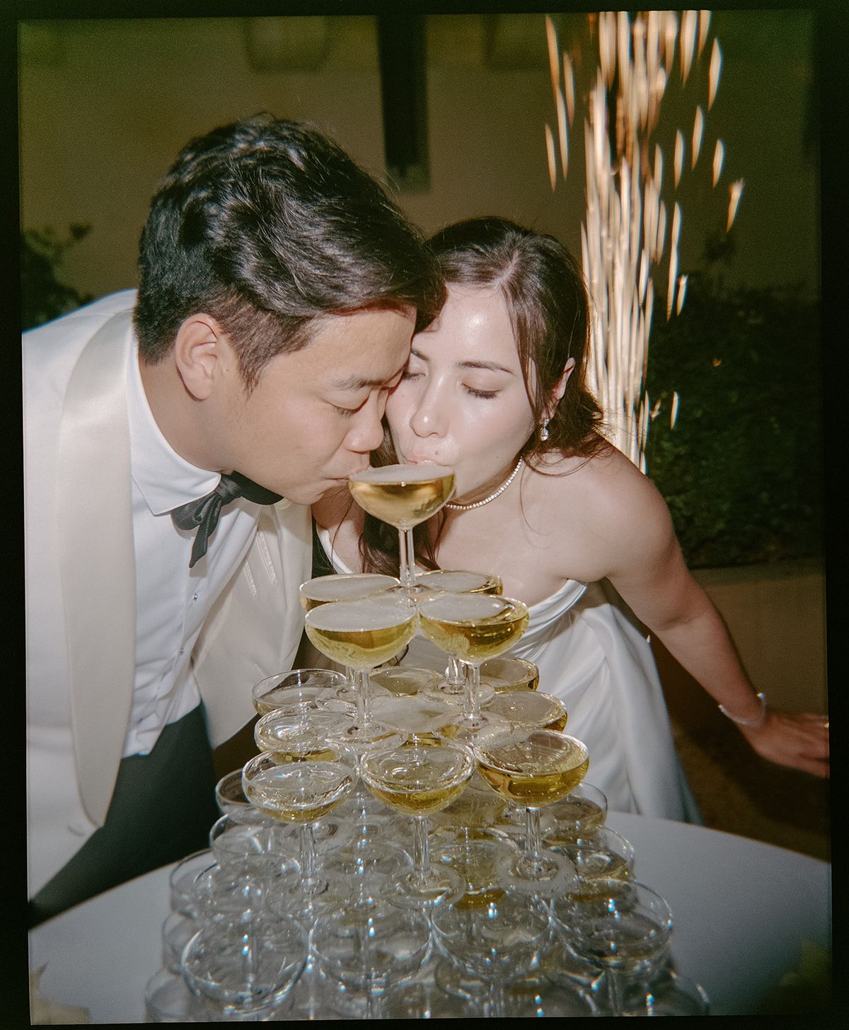 Carina and Stefan sipping from the same coupe at the top of the champagne tower