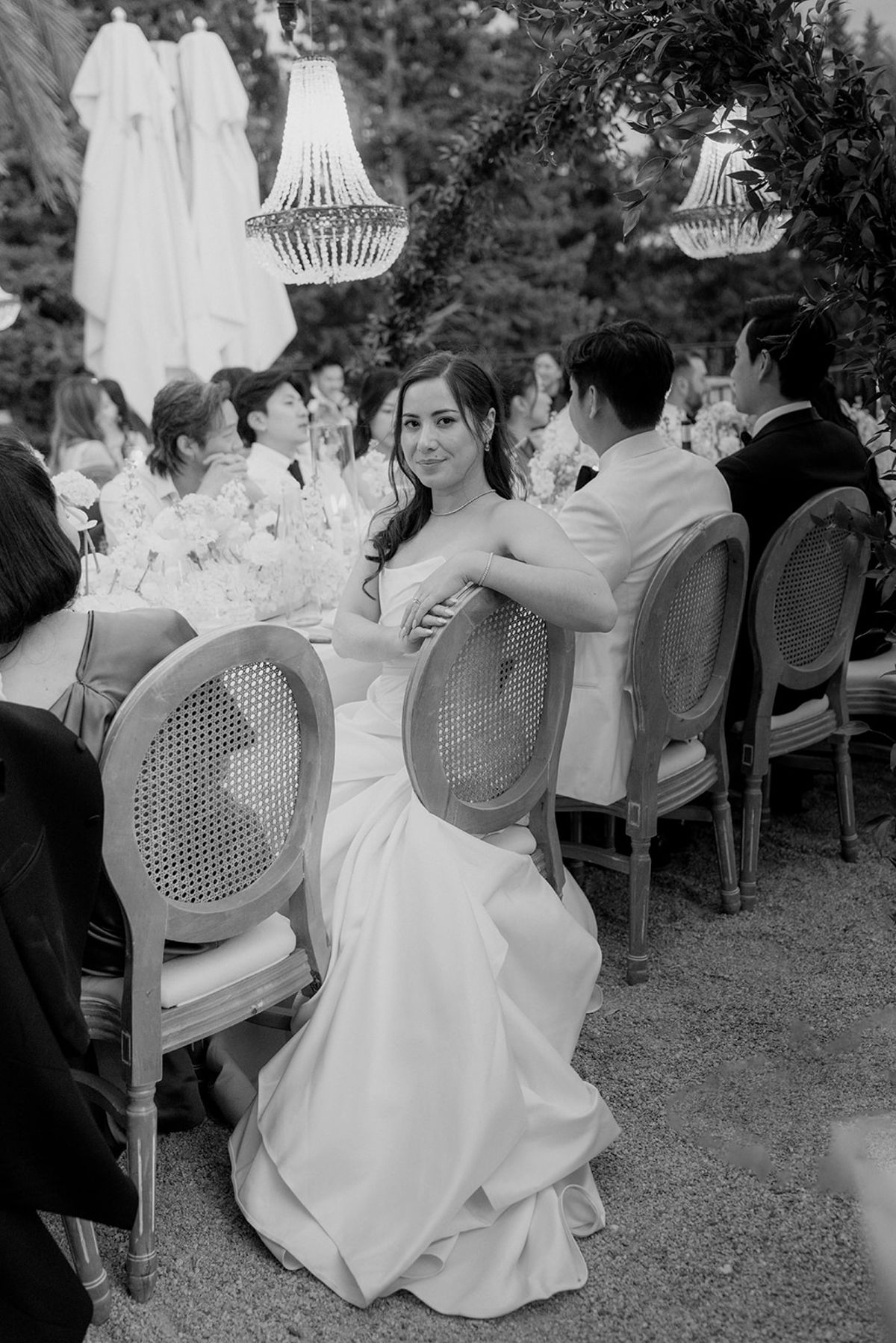 Black and white view of Carina seated sideways on her chair at the dinner table