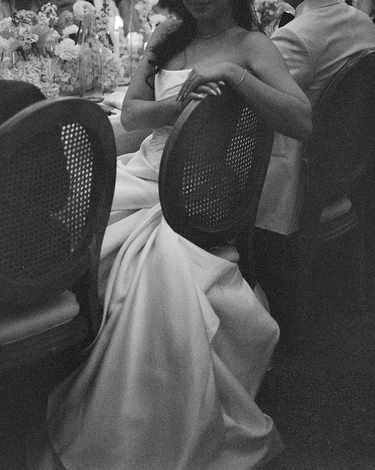 Black and white close view of the bride's gown as she sits at the dinner table