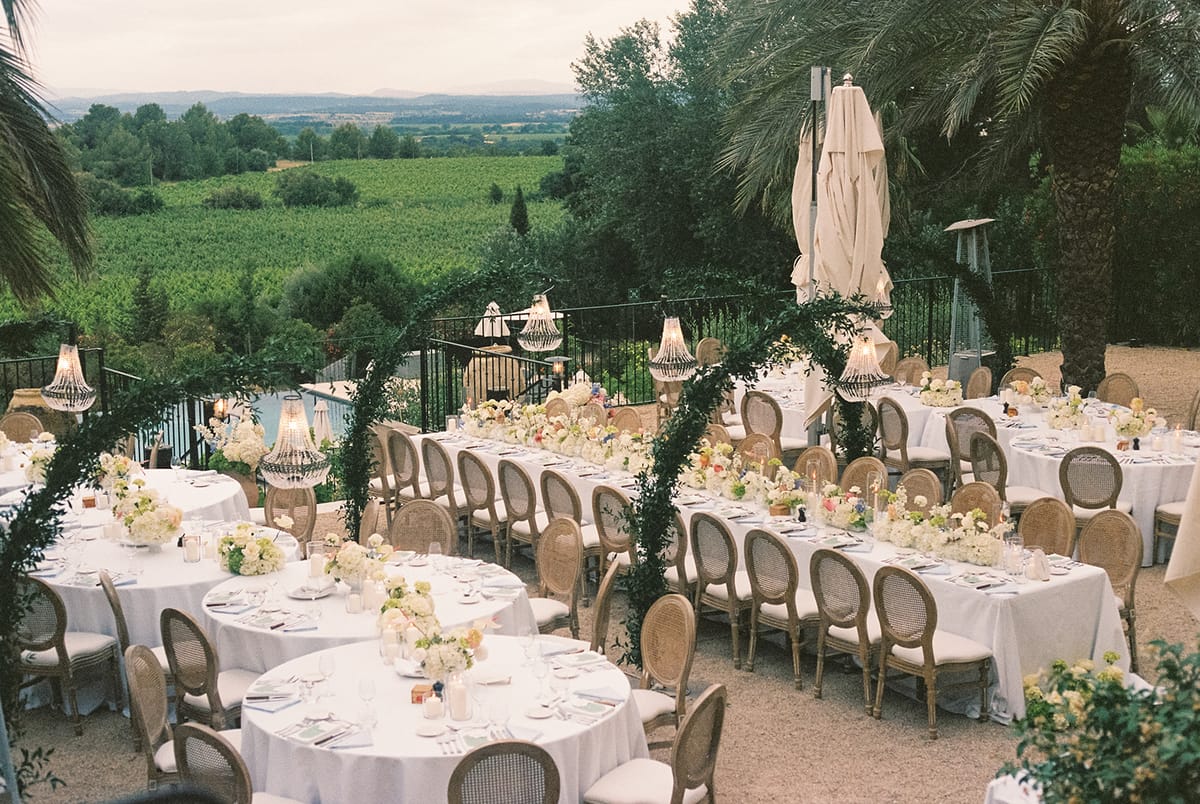 Dinner tables beneath green arches on a terrace overlooking the vineyards