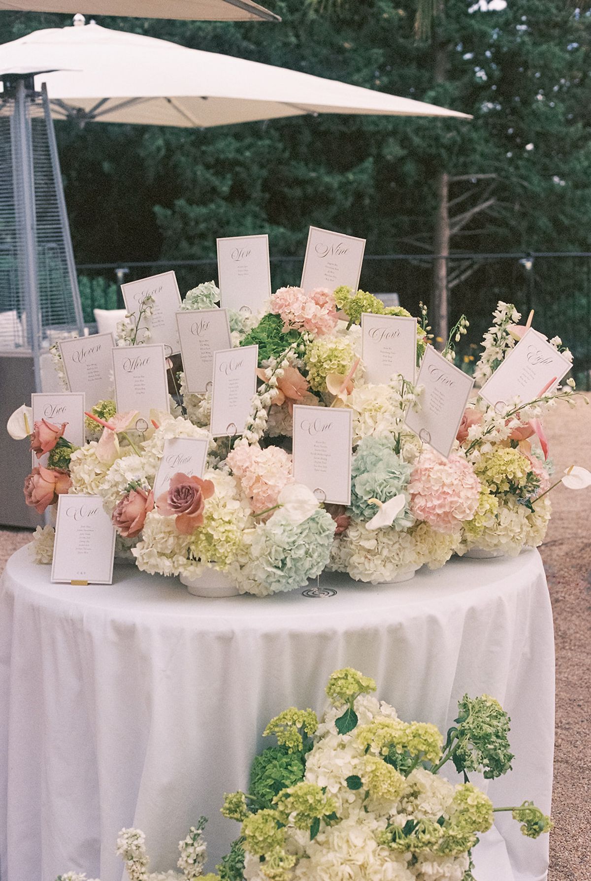 Escort cards set into pastel hydrangea and roses on a round table