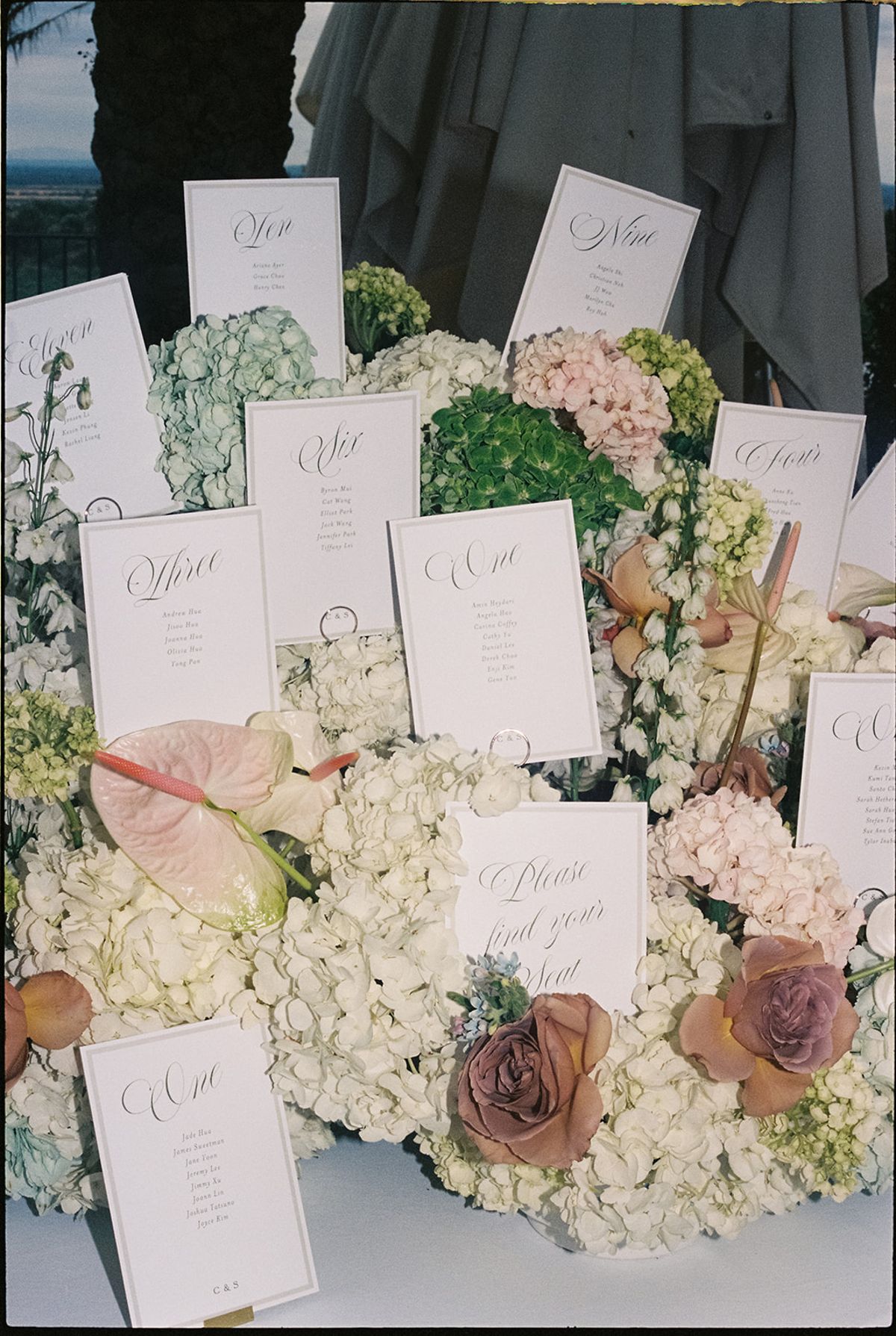Close view of escort cards among hydrangea, dusty-rose roses and anthurium