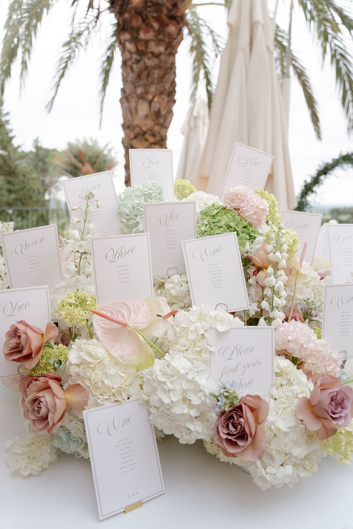 Escort cards rising from a bed of hydrangea and dusty-rose roses