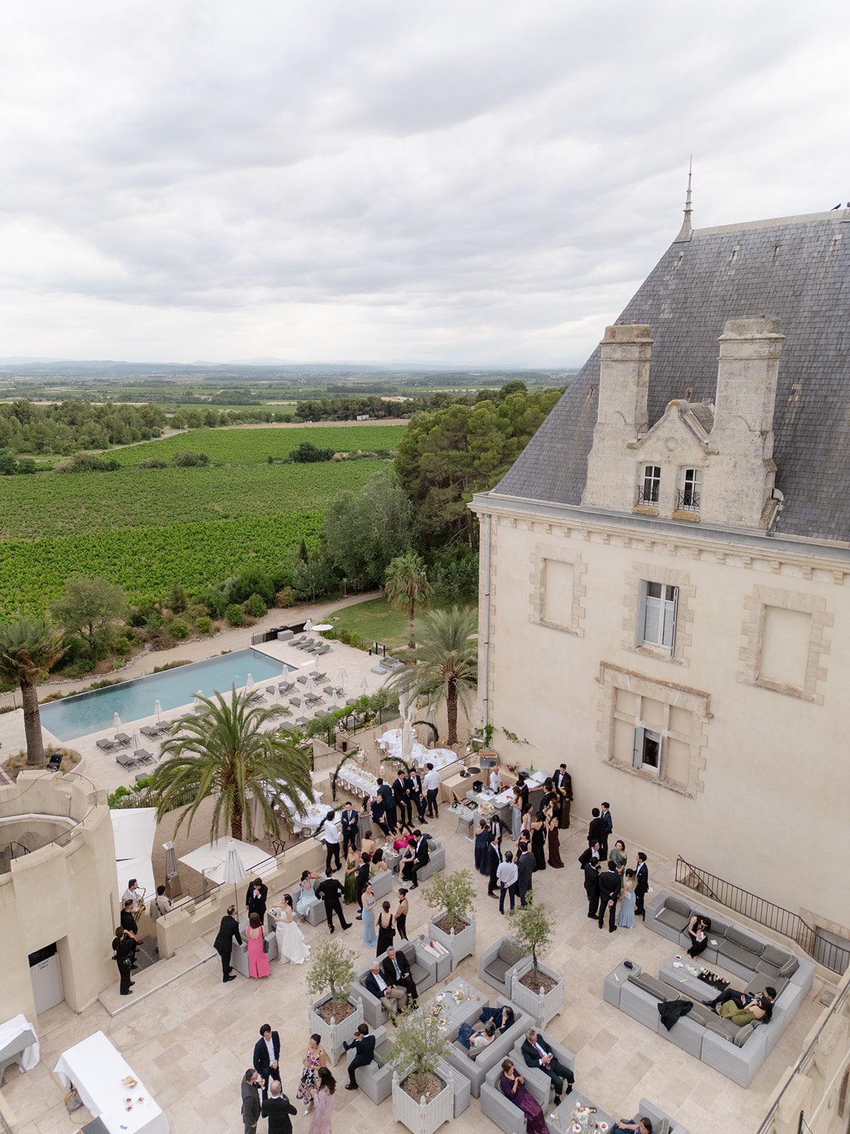 Aerial view of guests on a raised terrace above the pool at Château les Carrasses, vineyards beyond