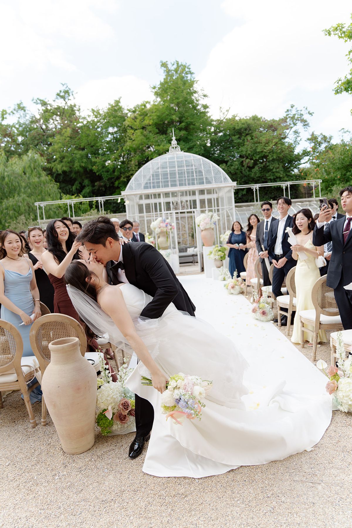 Stefan dipping Carina for a kiss in the aisle as guests cheer around them