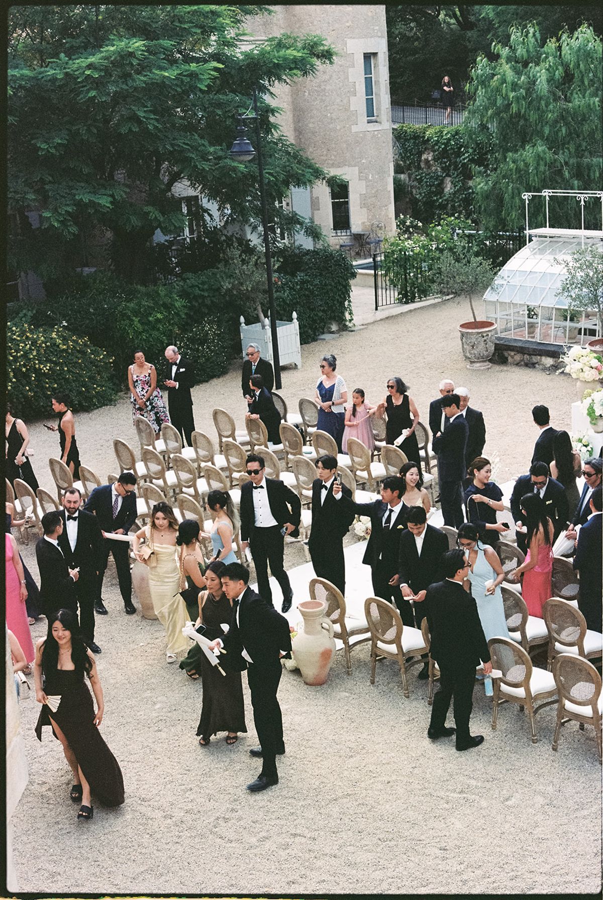 High view of guests standing among the ceremony chairs in the courtyard after the vows