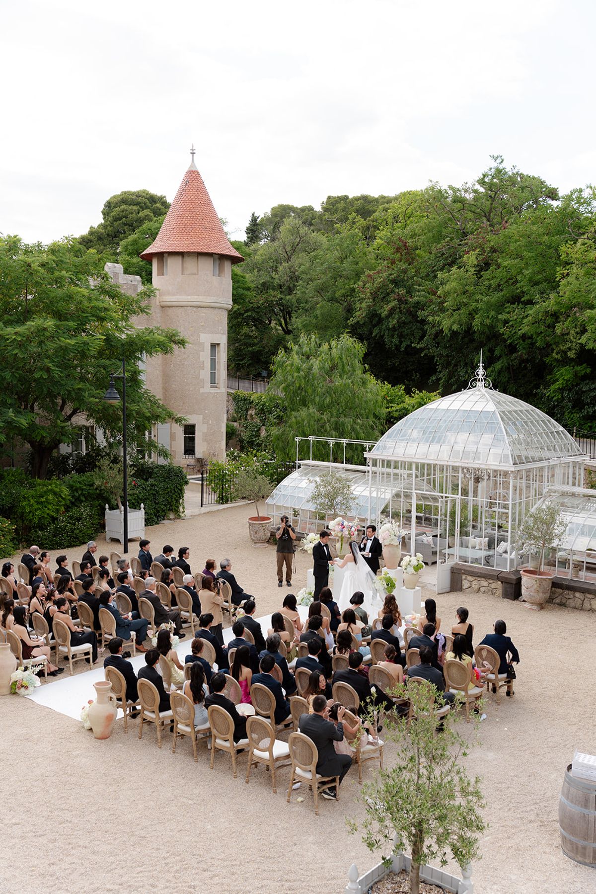 High view of the ceremony in the courtyard with the greenhouse and a turret beyond