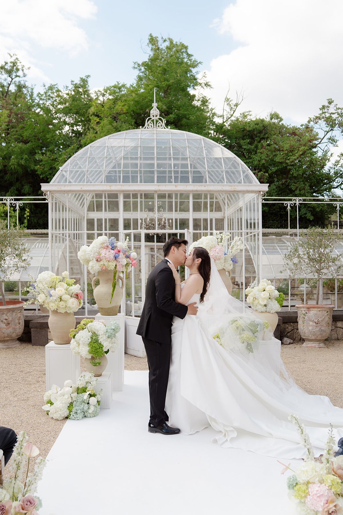 Carina and Stefan kissing at the end of the ceremony in front of the glass greenhouse