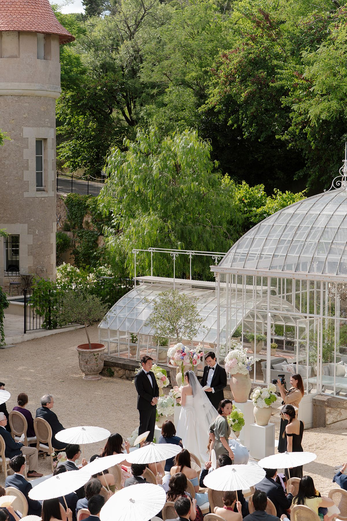 High view of the ceremony at the greenhouse with guests shaded by white paper parasols