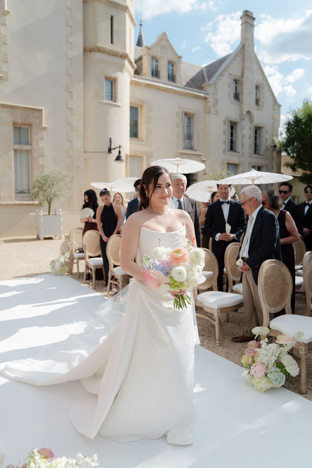 Carina walking up the aisle with her bouquet as guests stand on either side
