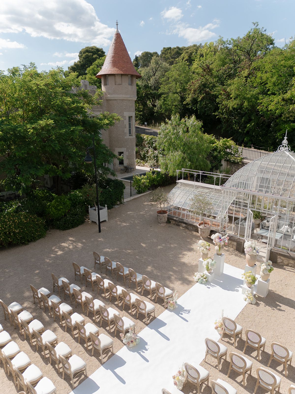 High view of the ceremony seating in the courtyard between the greenhouse and a tower of Château les Carrasses