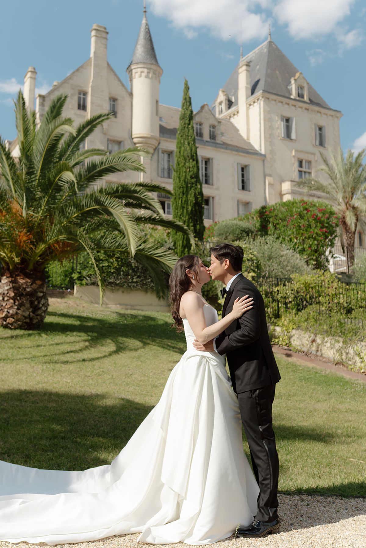 Carina and Stefan kissing on the lawn in front of the château, her train spread on the grass