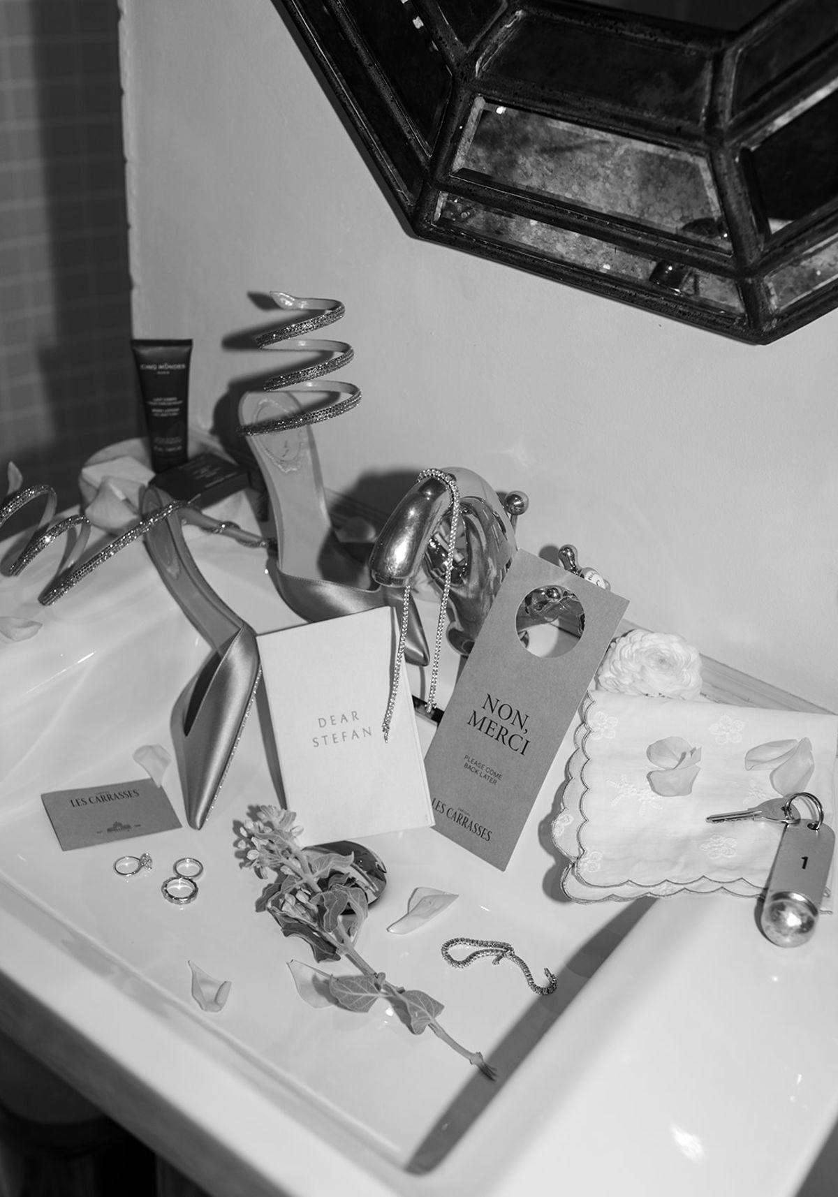 Black and white arrangement of jewellery, perfume and stationery on a marble surface