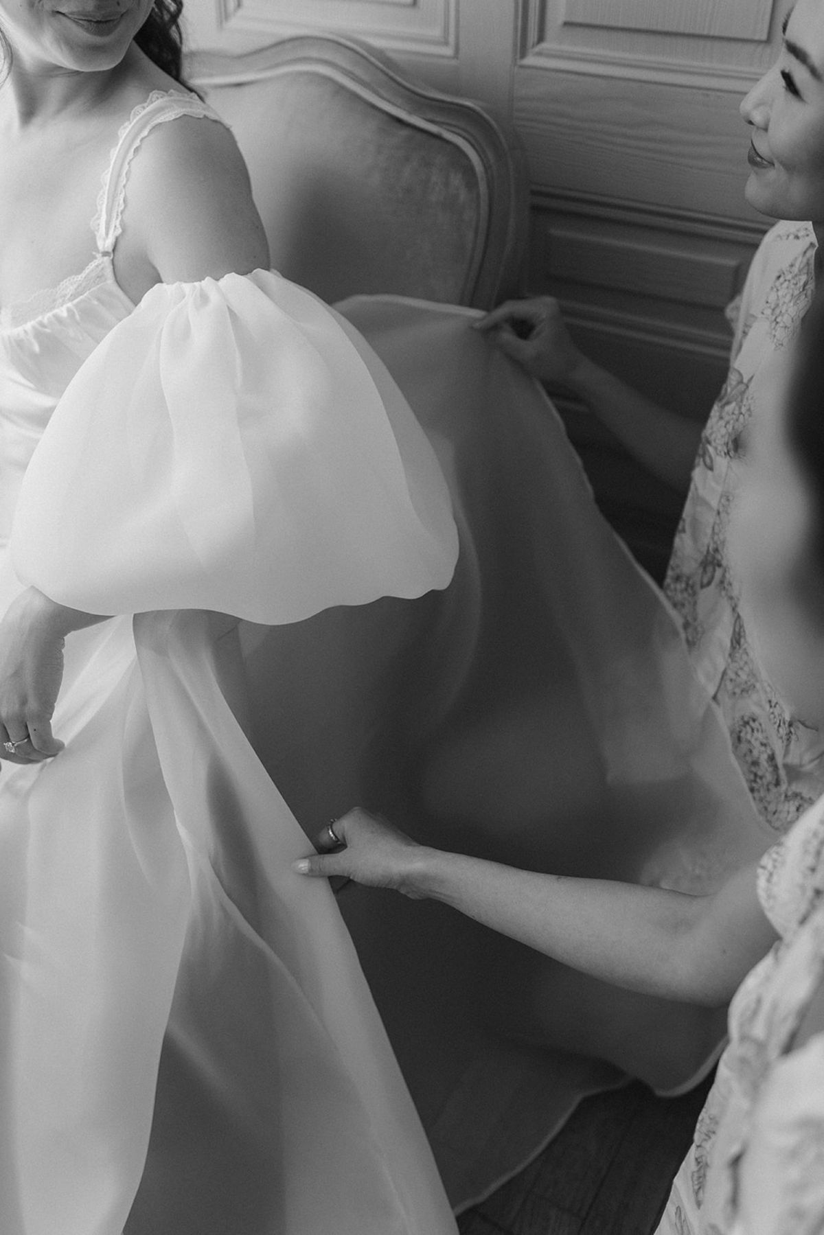 Black and white close view of hands smoothing the sheer puff sleeve and skirt of a robe cape