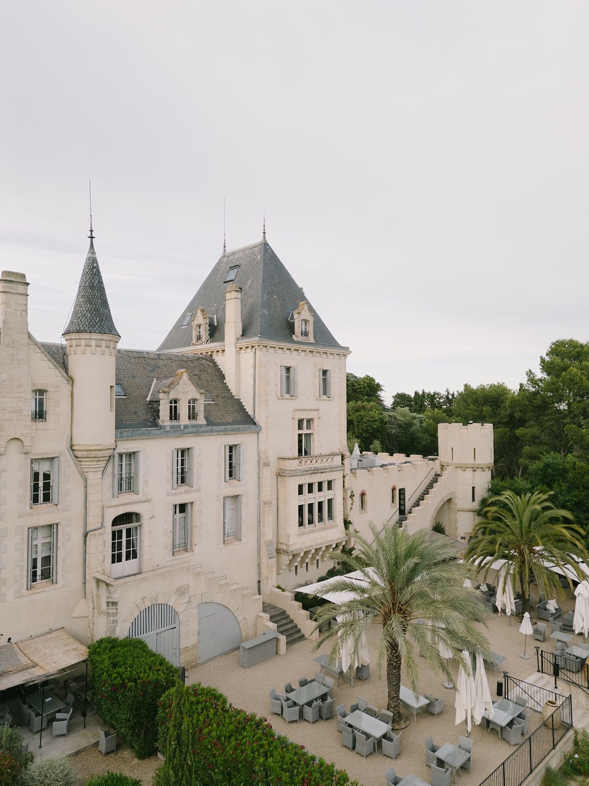 The towers of Château les Carrasses above a terrace of palms and parasols