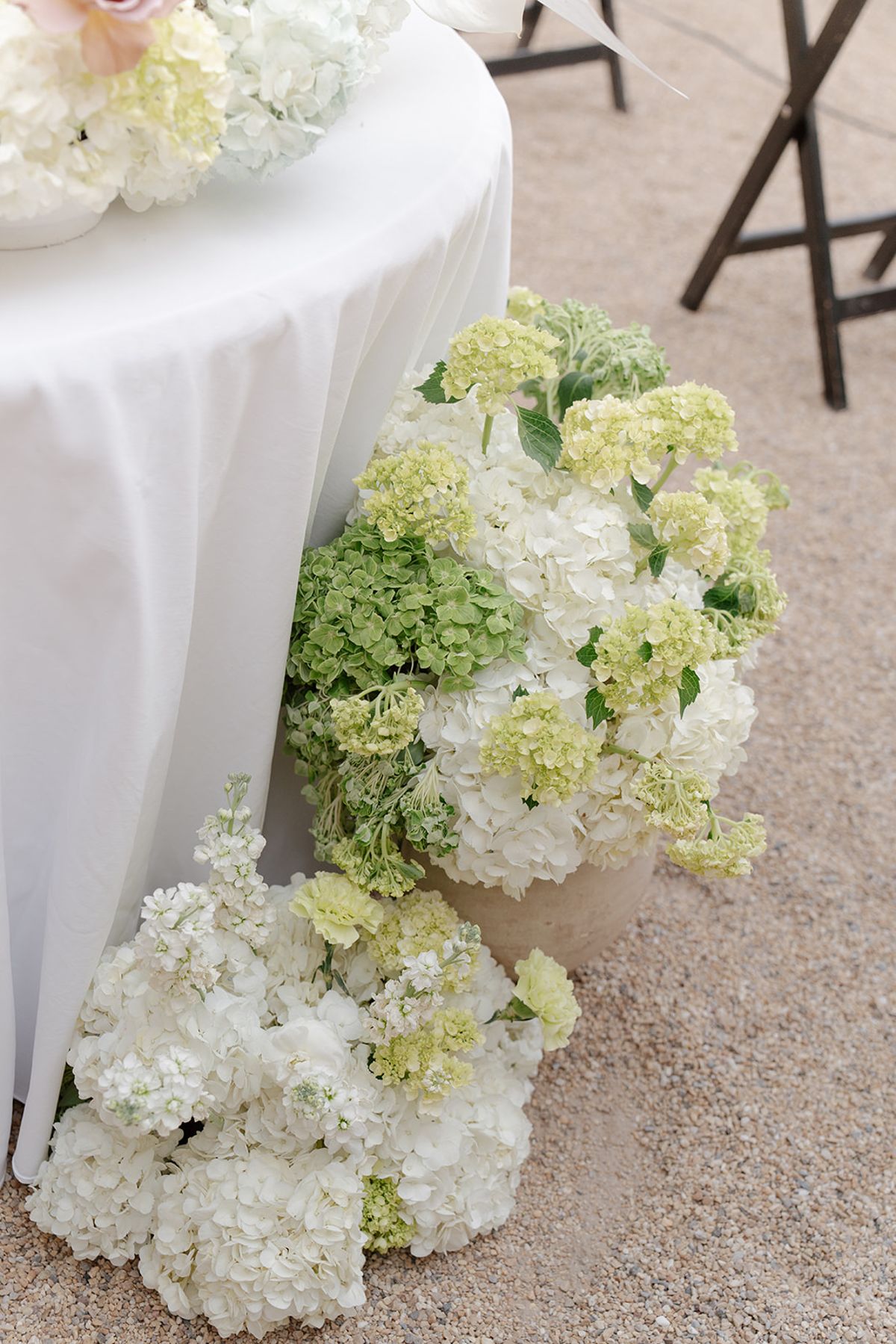 Clusters of white and green hydrangea at the foot of a table draped in white