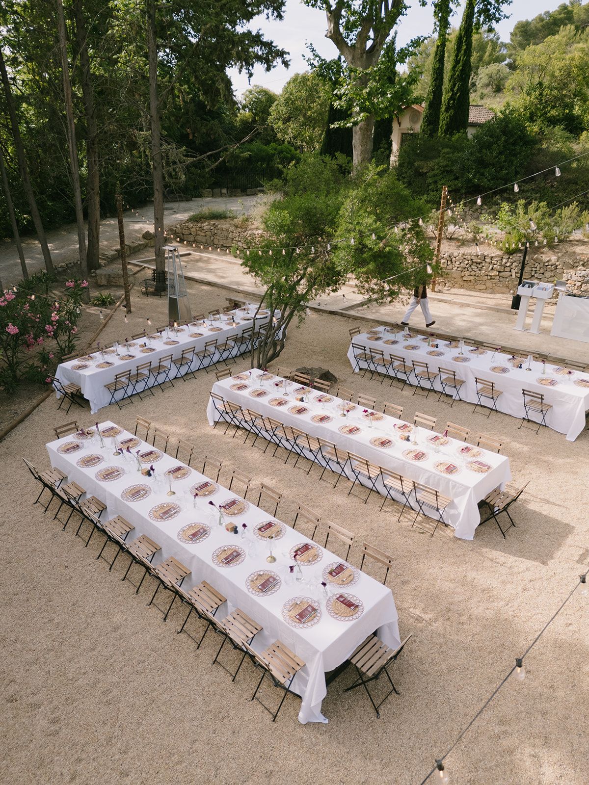 Tables set in white on a garden terrace among trees and oleander at the welcome party the day before
