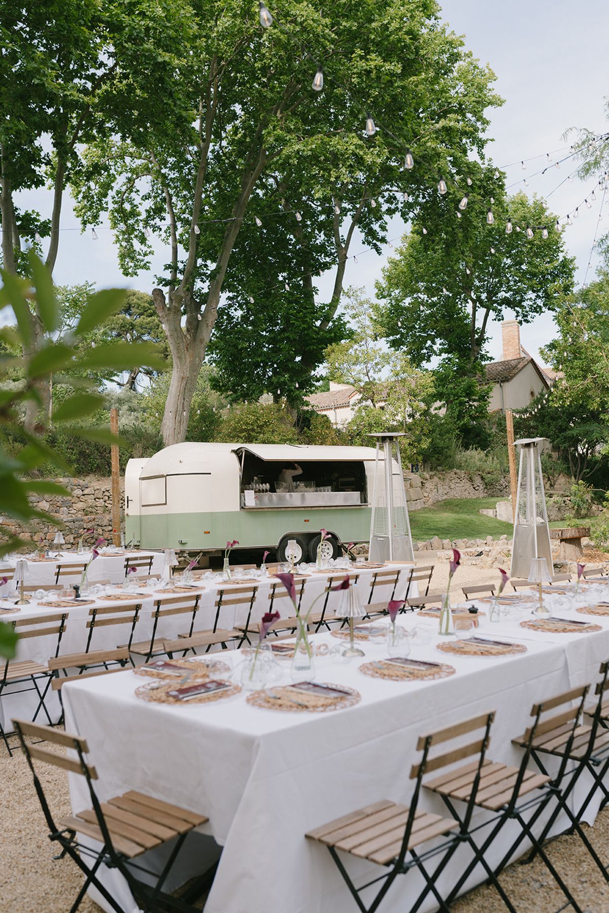 Tables on a garden terrace with a vintage cream and green trailer bar at the welcome party the day before