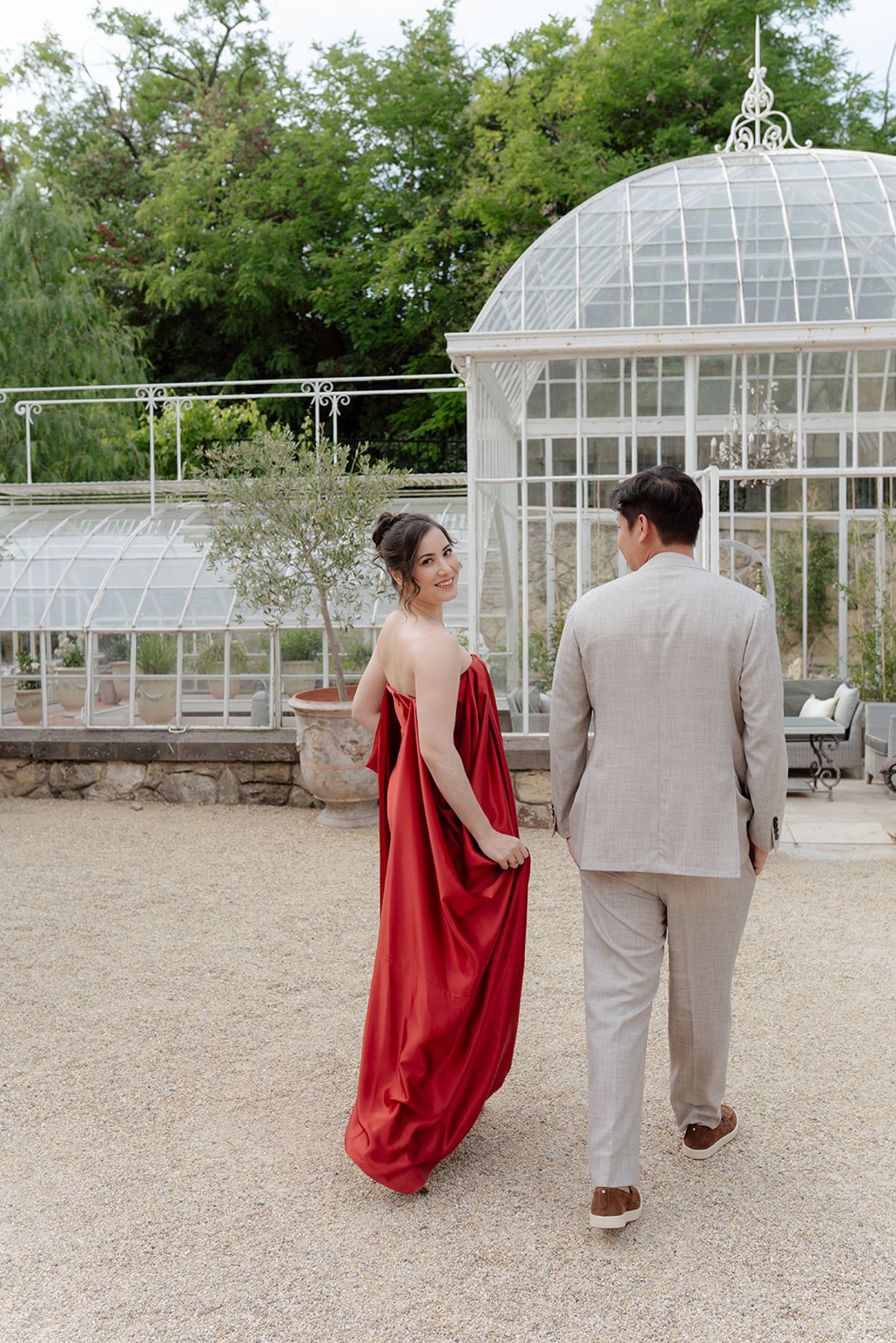Carina and Stefan walking towards the glass greenhouse, Carina looking back, at the welcome party the day before