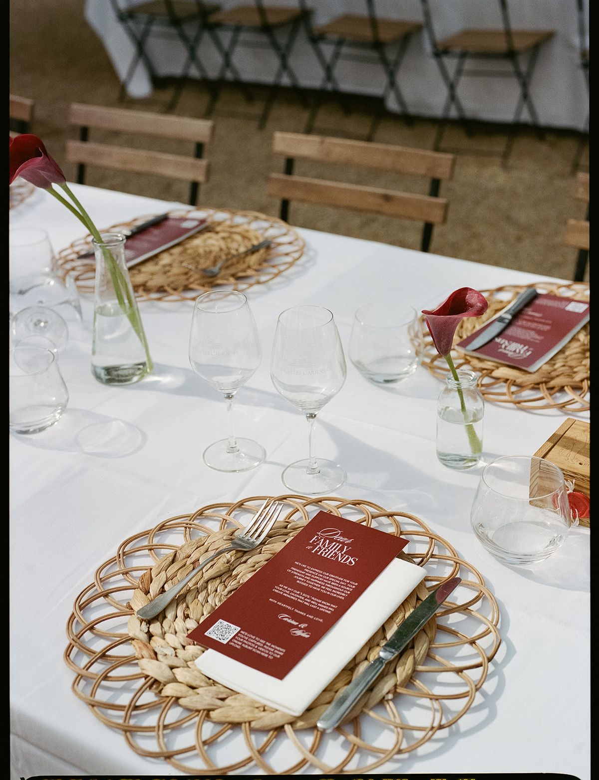 A place setting with a woven charger, burgundy menu and wine glasses at the welcome party the day before