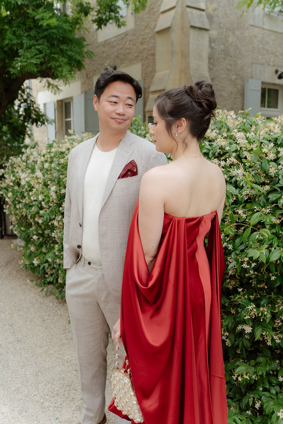 Stefan with a red pocket square smiling beside Carina, seen from behind in red, at the welcome party the day before