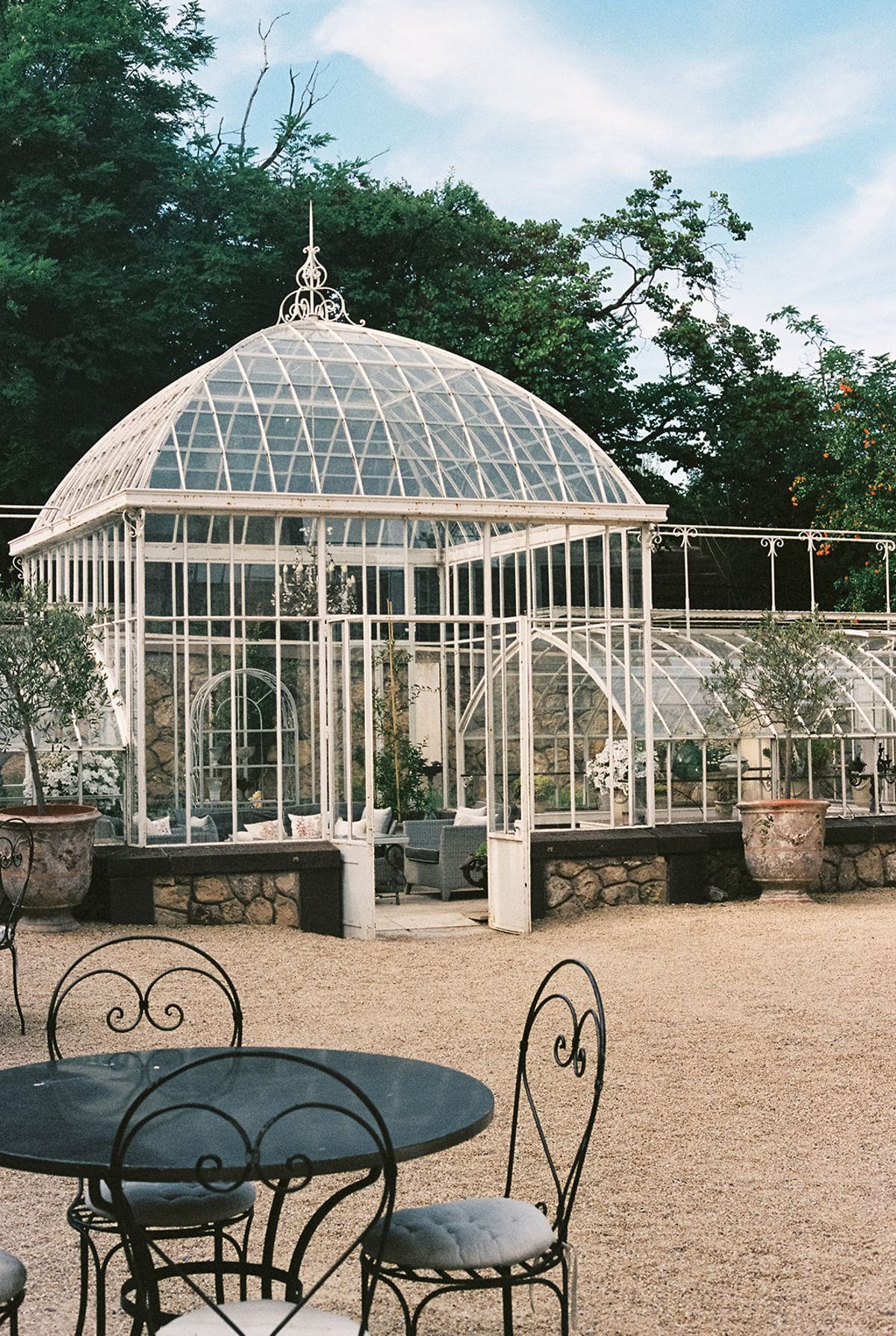 The glass greenhouse and a wrought-iron bistro table, photographed at the welcome party the day before