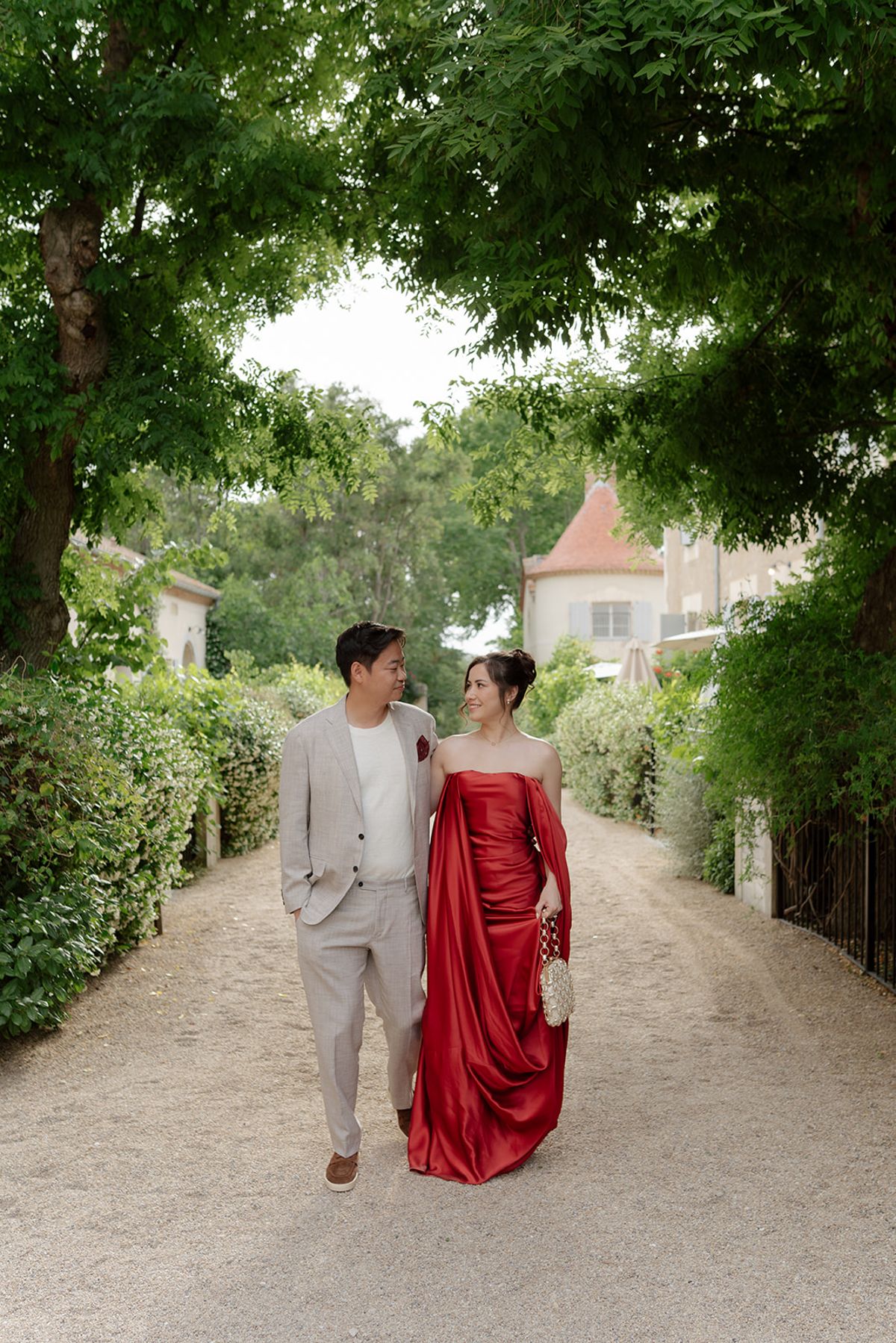 Carina and Stefan walking arm in arm down a tree-lined drive at the welcome party the day before