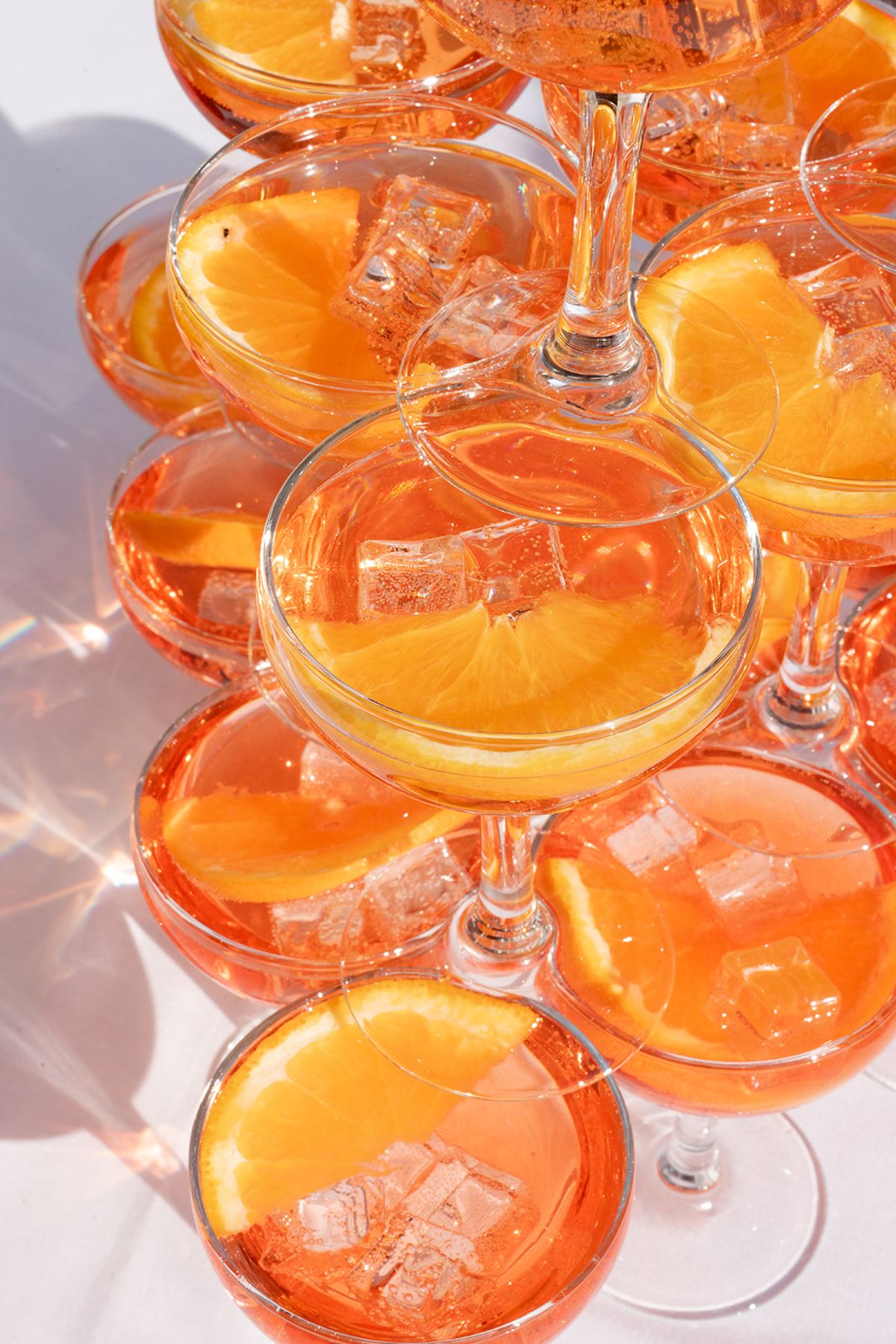 Close view of a tower of coupes filled with spritz, ice and orange slices