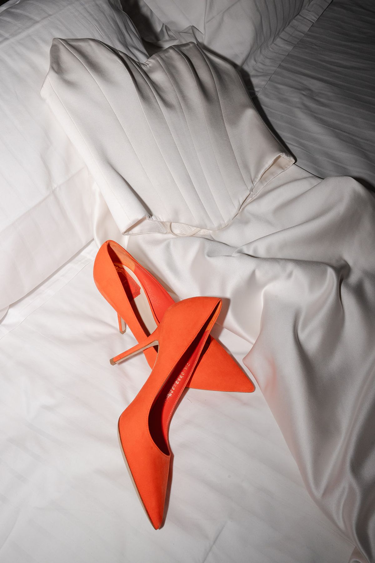 Orange suede heels on white bed linen