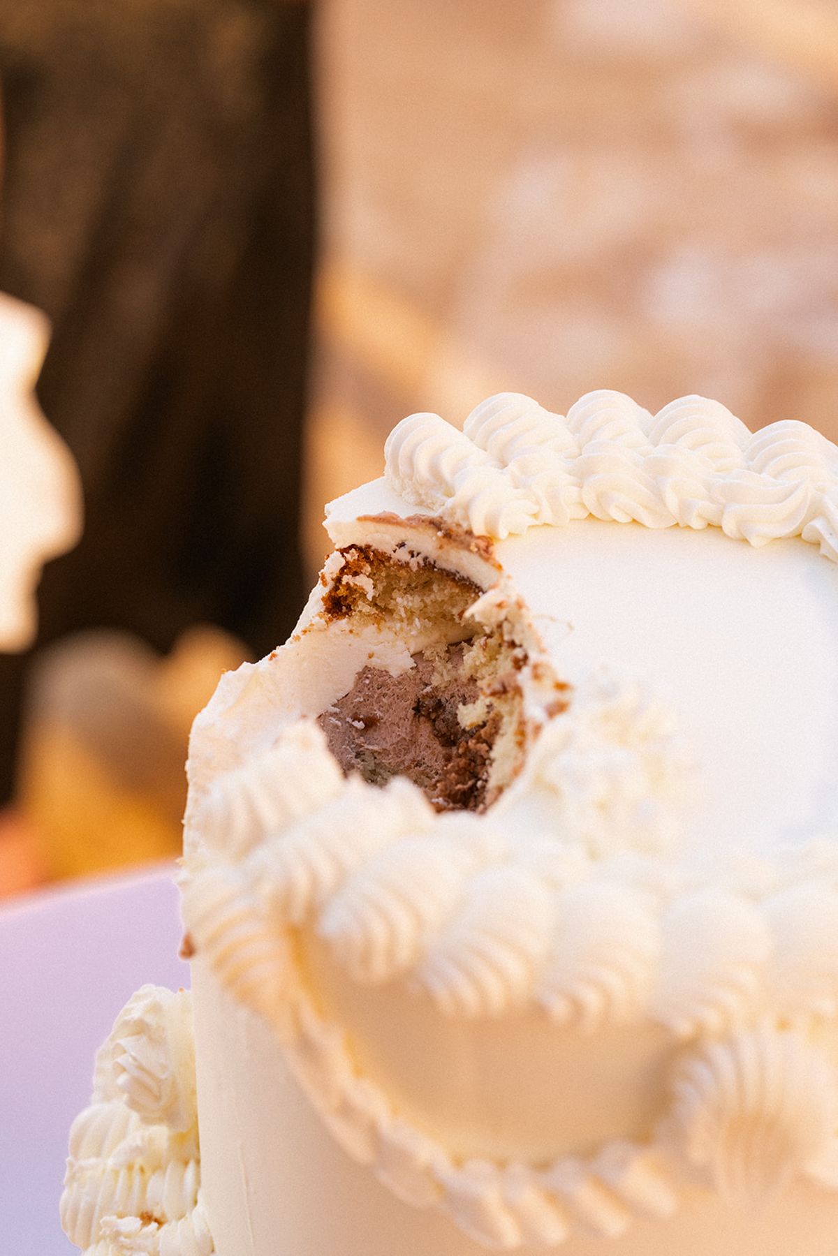 Close detail of the cut wedding cake, its piped white icing and layered sponge visible in cross-section.