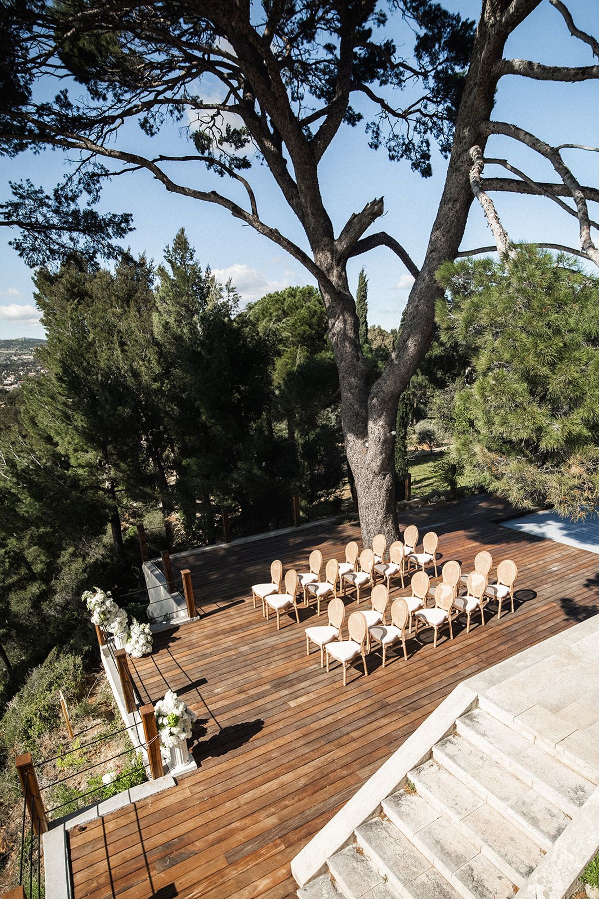 The ceremony deck set with cane-back chairs in two rows, white floral pedestals marking the aisle end.