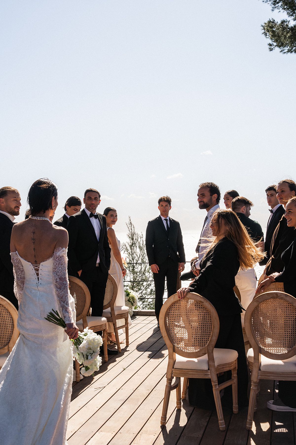 Guests stand and turn to watch as the bride arrives on the ceremony deck.