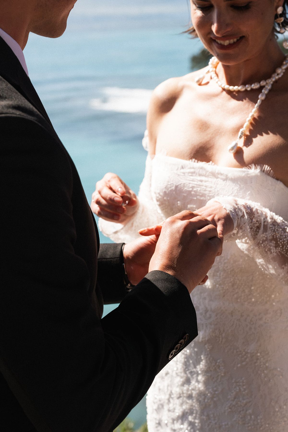 The bride and groom stand together at the front of the ceremony deck before their seated guests.