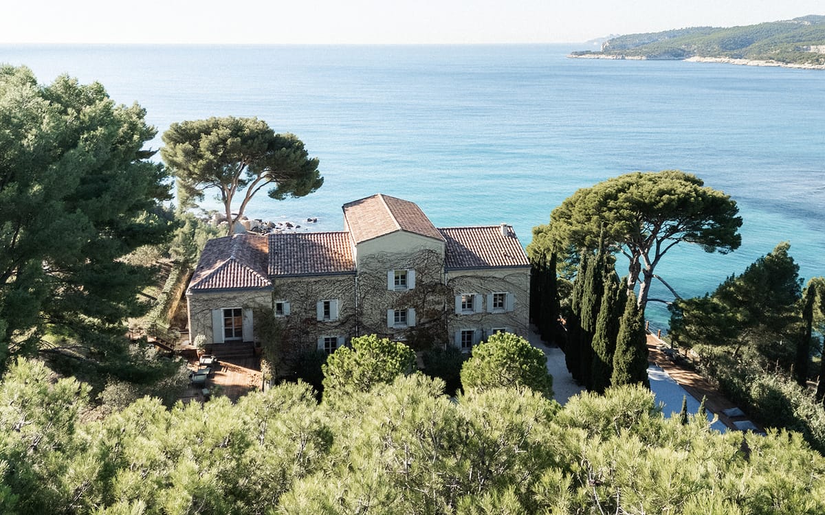 An aerial view of the estate perched above the Cassis coastline, pine trees and turquoise water surrounding it.