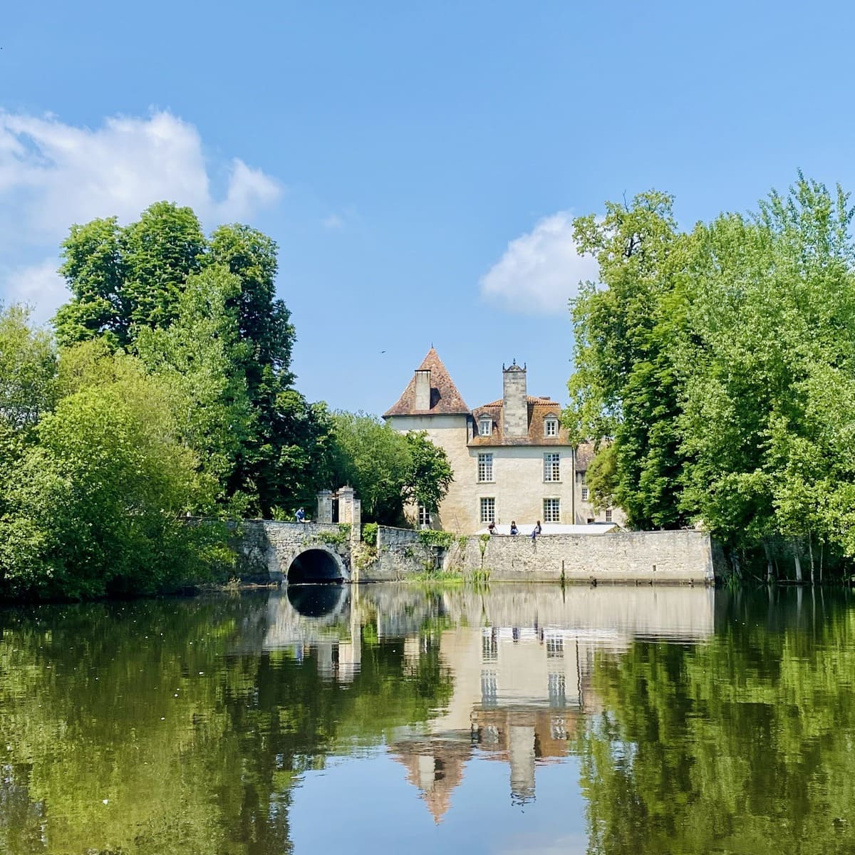 Château de la Faye seen across the water, its tower reflected in the pond