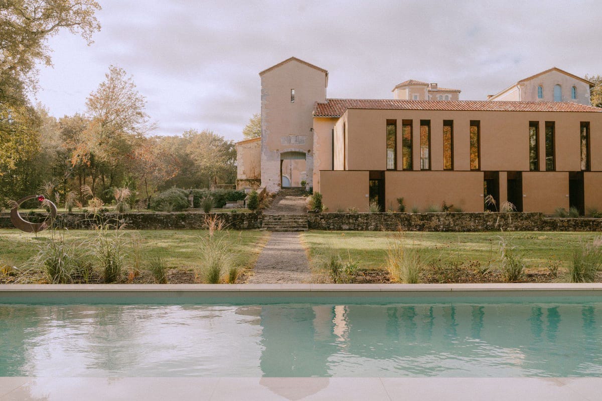 The swimming pool and lawn in front of the château's modern extension building in autumn.