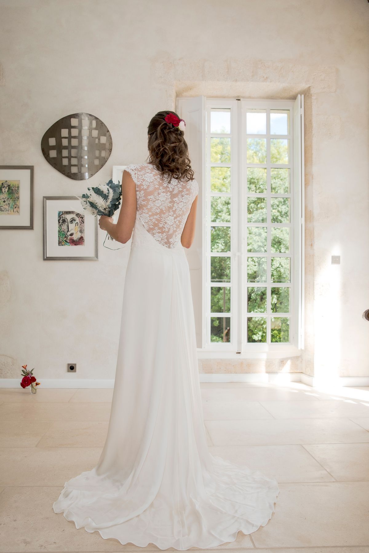 A bride in a lace-back gown in a naturally lit interior room