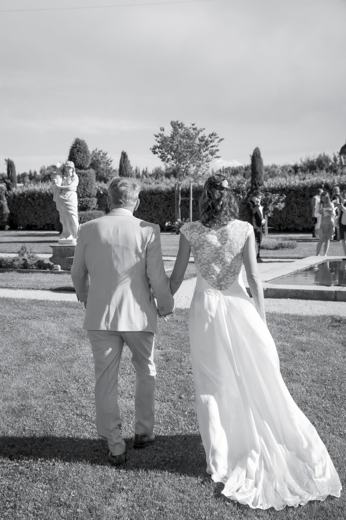 A bride walking through the gardens with her father before the ceremony