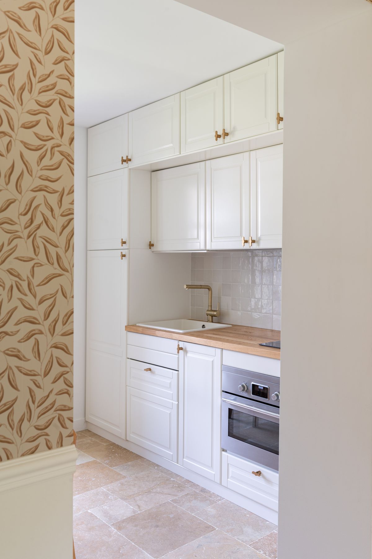 The guest house kitchen with cream cabinetry, brass fittings, an oven and a wood worktop