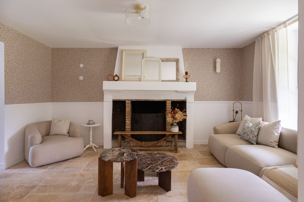 The guest house sitting room with a stone fireplace, curved sofas and a marble coffee table