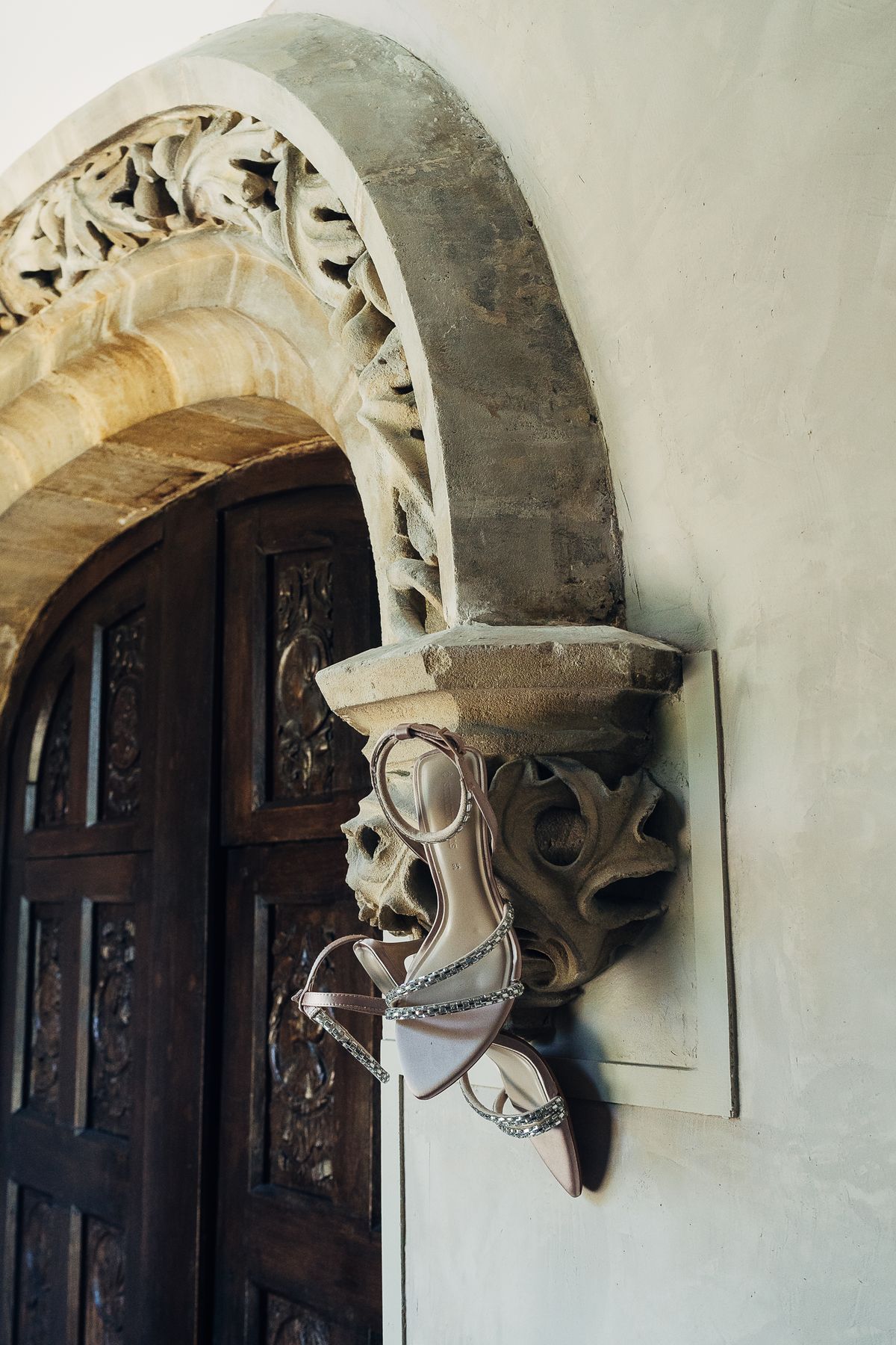 Bridal shoes hung from a carved gothic stone archway inside the château