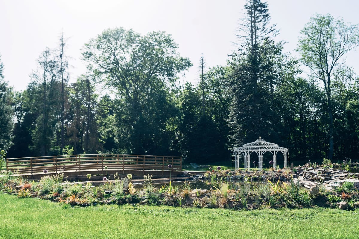 The water garden with its curved bridge and the gloriette beyond, backed by mature parkland trees
