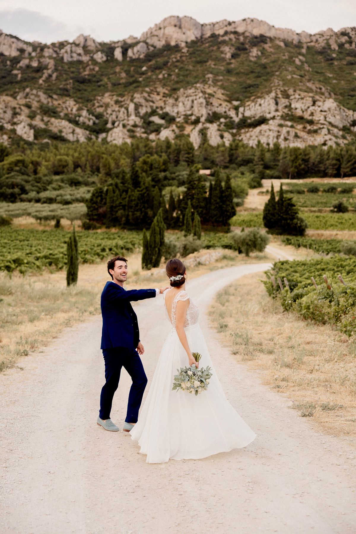 A couple on a gravel track through the vineyards at Domaine ODDO Vallon des Glauges, below the limestone cliffs of the Alpilles