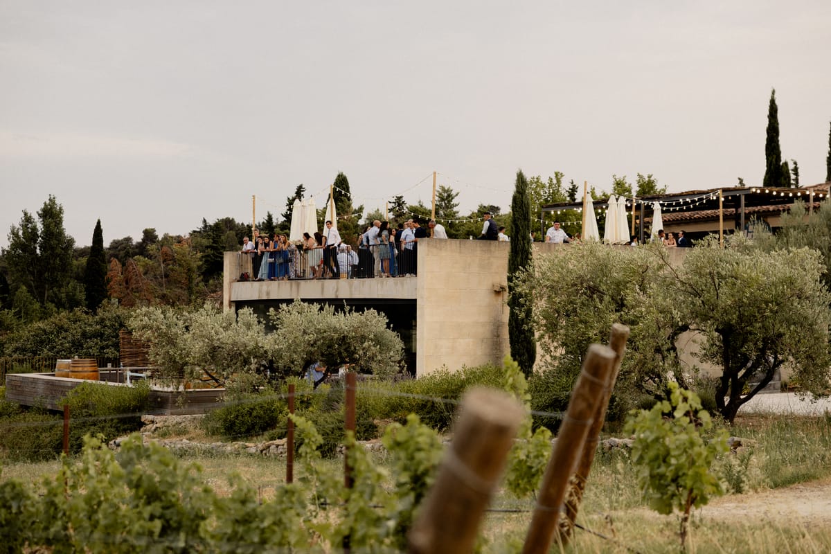 Guests gather on the terrace of the estate building at Domaine ODDO Vallon des Glauges, seen across the vines and olive trees