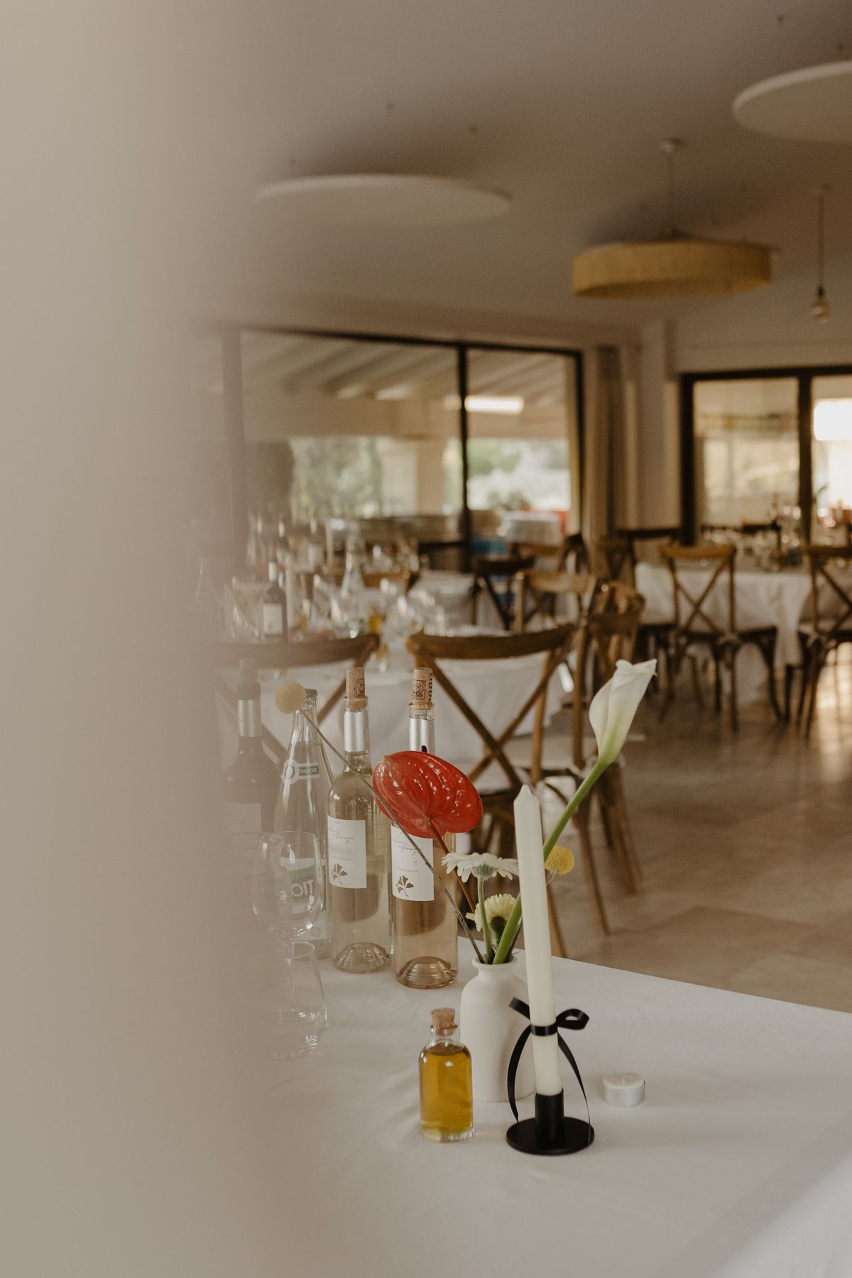 Estate wine and olive oil on a dinner table, with the reception room at Domaine ODDO Vallon des Glauges laid behind