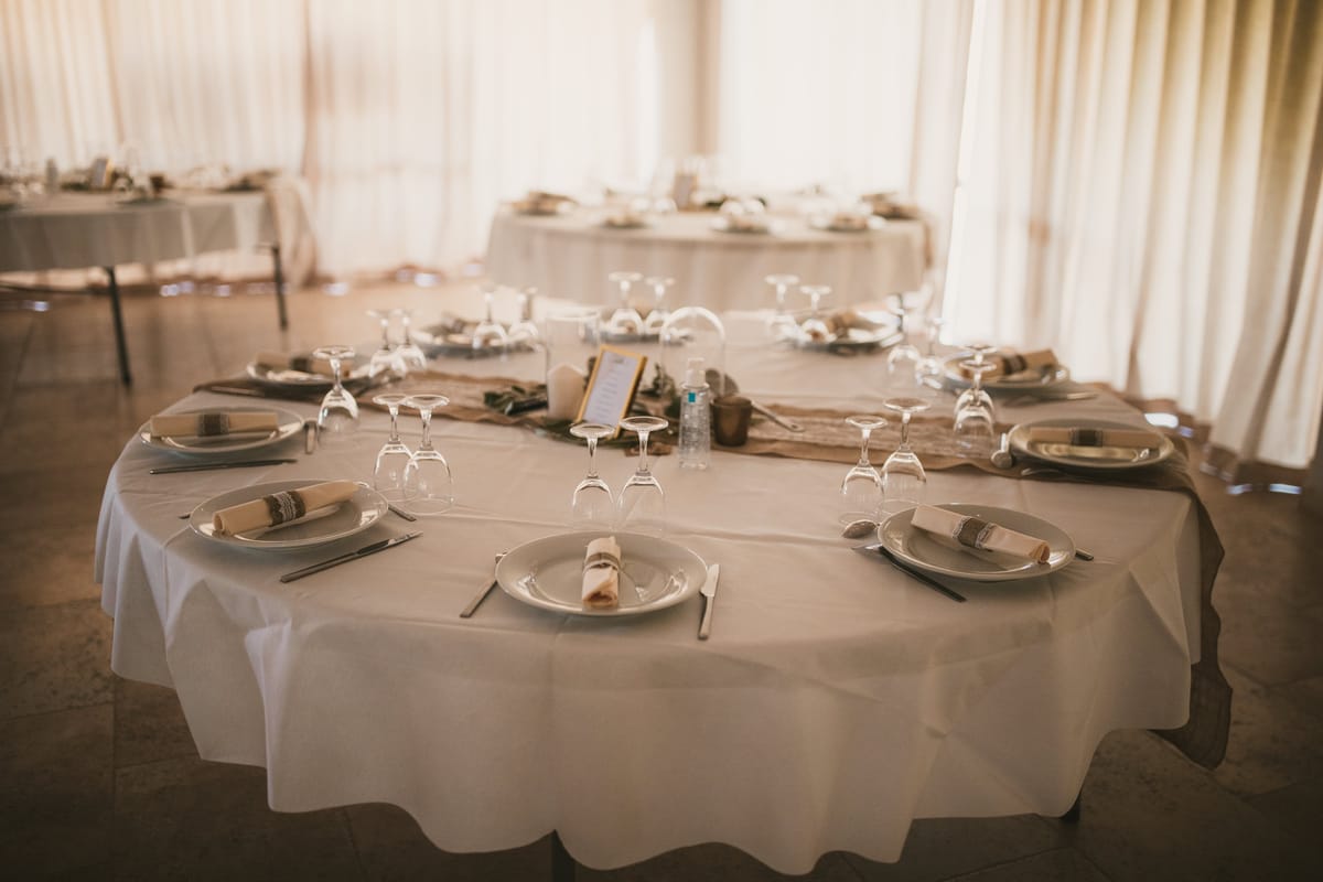 A round table laid with white linen, glasses and folded napkins in the reception room at Domaine ODDO Vallon des Glauges