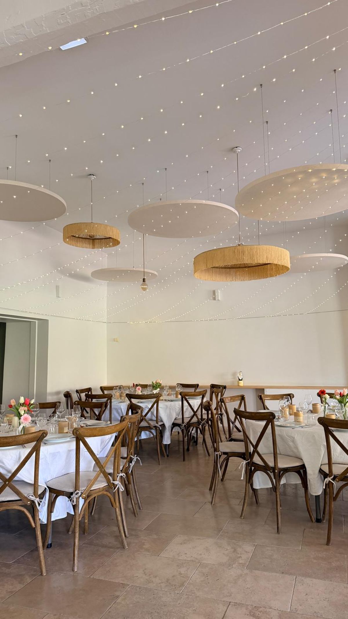 The reception room at Domaine ODDO Vallon des Glauges laid with tables and cross-back chairs under rattan pendant lights