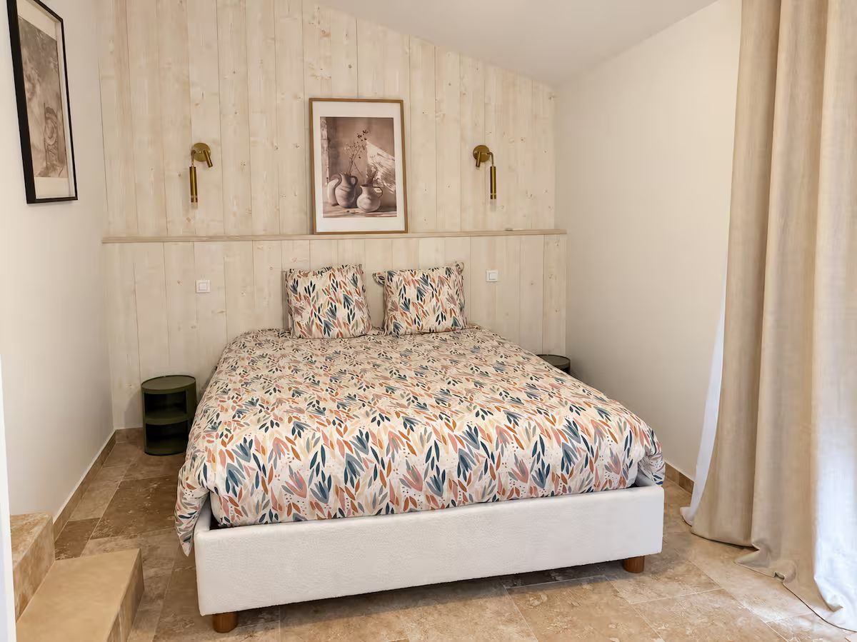 A bedroom at the Villa des Glauges with a floral bedspread and wood-panelled walls