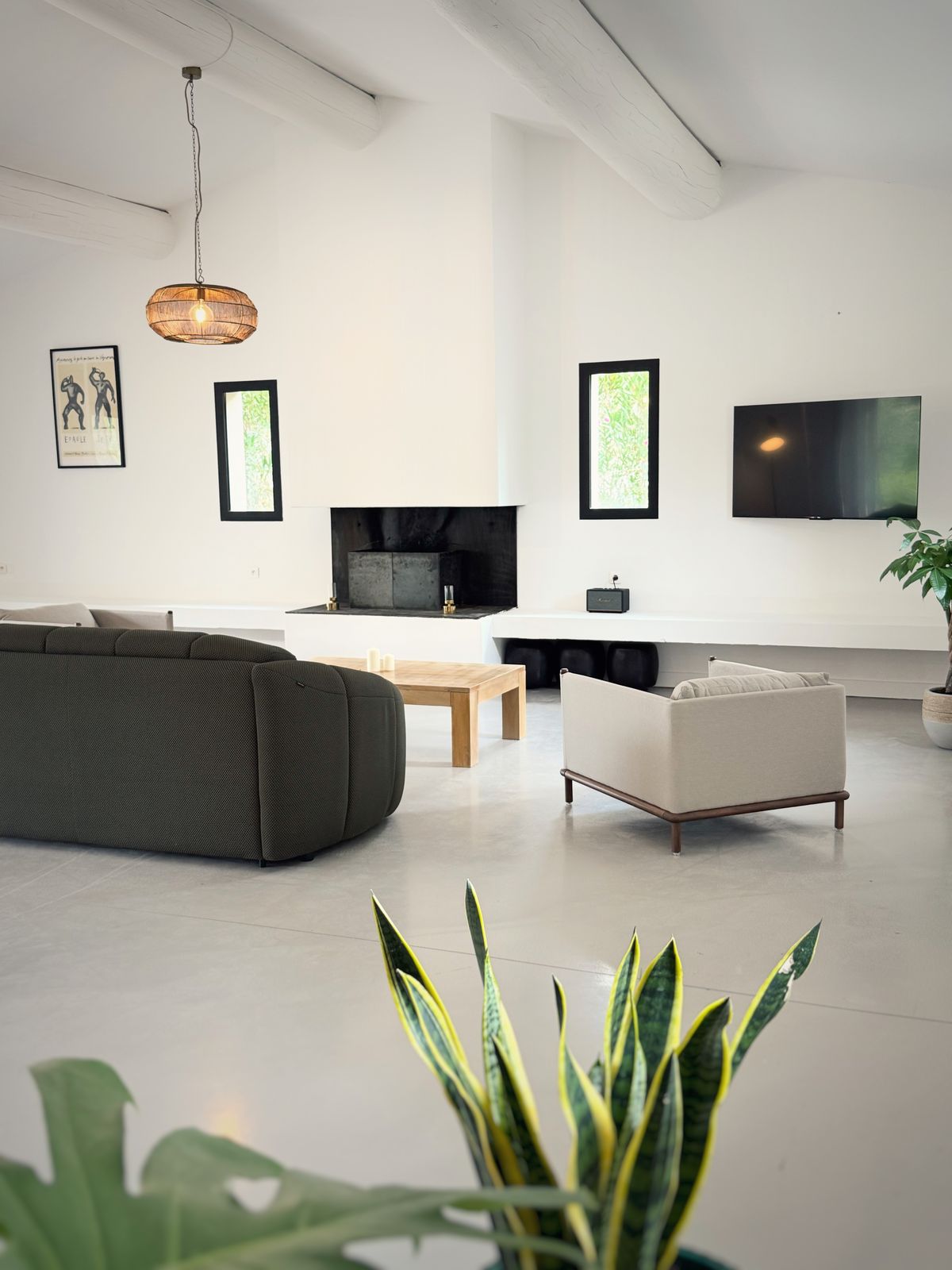 The living room of the Villa des Glauges with a deep green sofa, a fireplace and a television