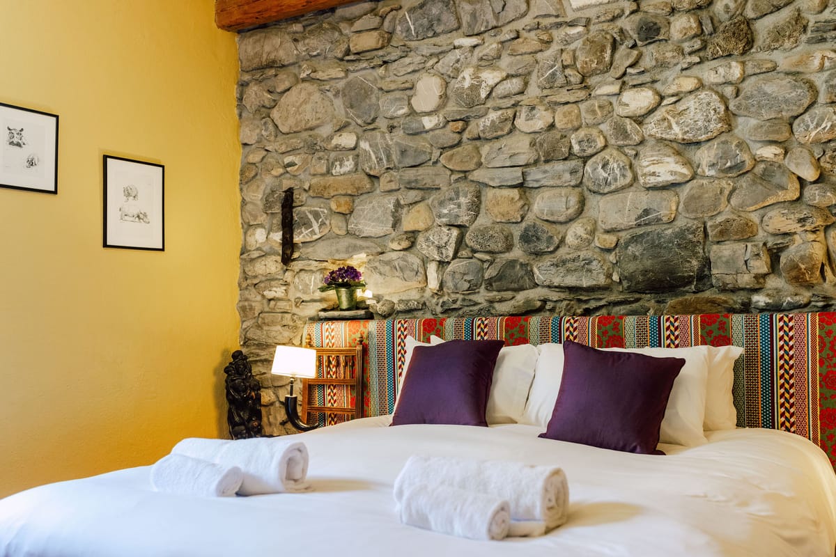 Guest bedroom with an exposed stone wall and a double bed